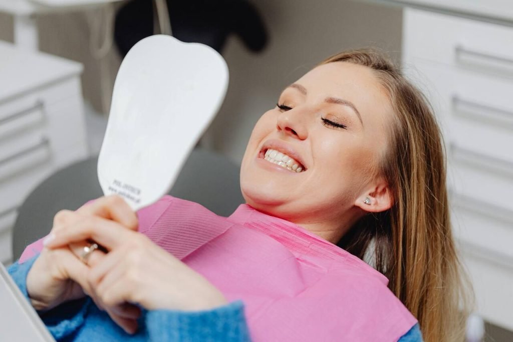 Woman smiling at her reflection after a dental check-up.