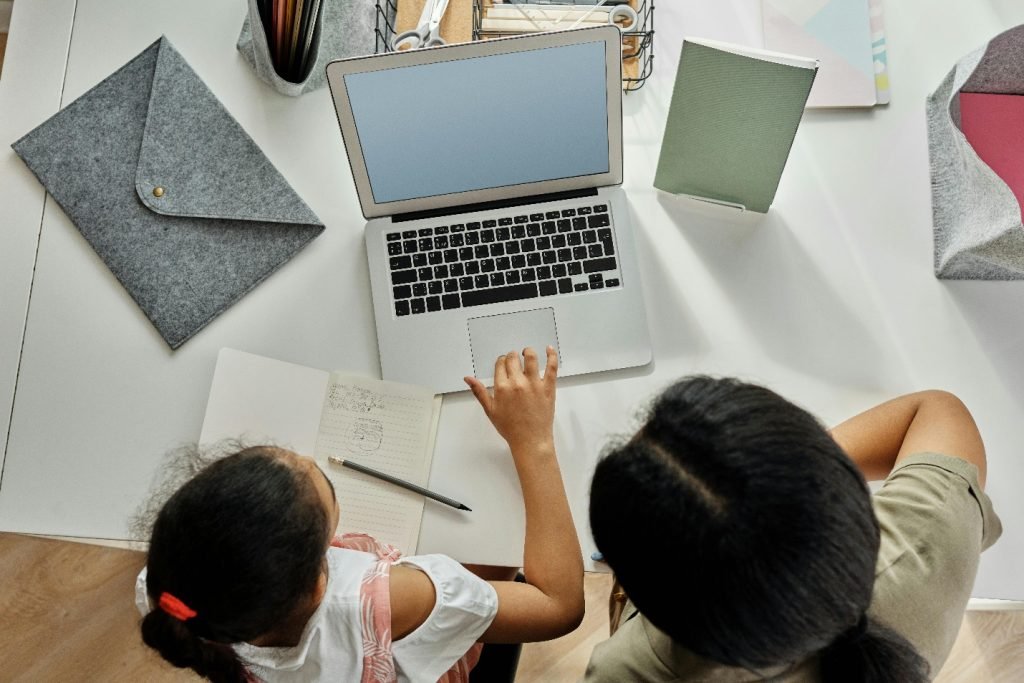Mother helping daughter with schoolwork on a laptop.