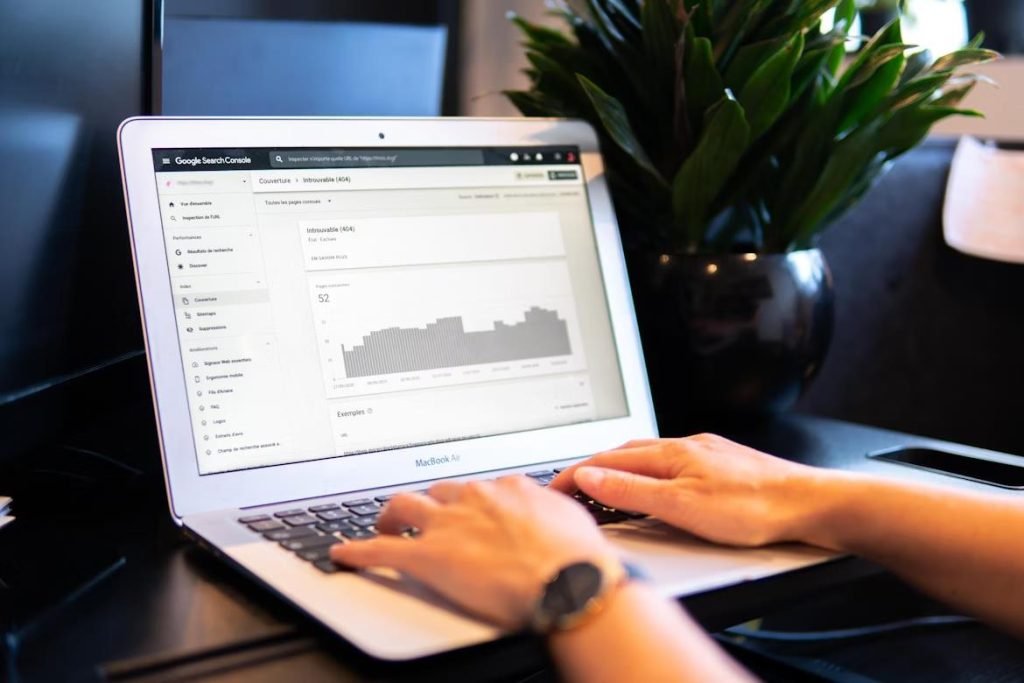 Why Your Home Décor Shop Needs a Local SEO Strategy A close-up of hands typing on a MacBook Air displaying Google Search Console showing 404 error data analysis. A plant is visible in the background.