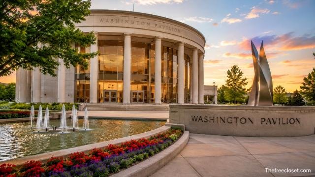 Washington Pavilion building with fountains, landscaped flowers, and a sunset sky.